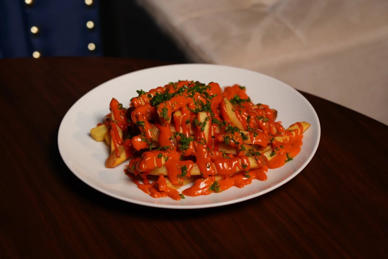 Gochujang feta fries topped with spring onion on a white plate
