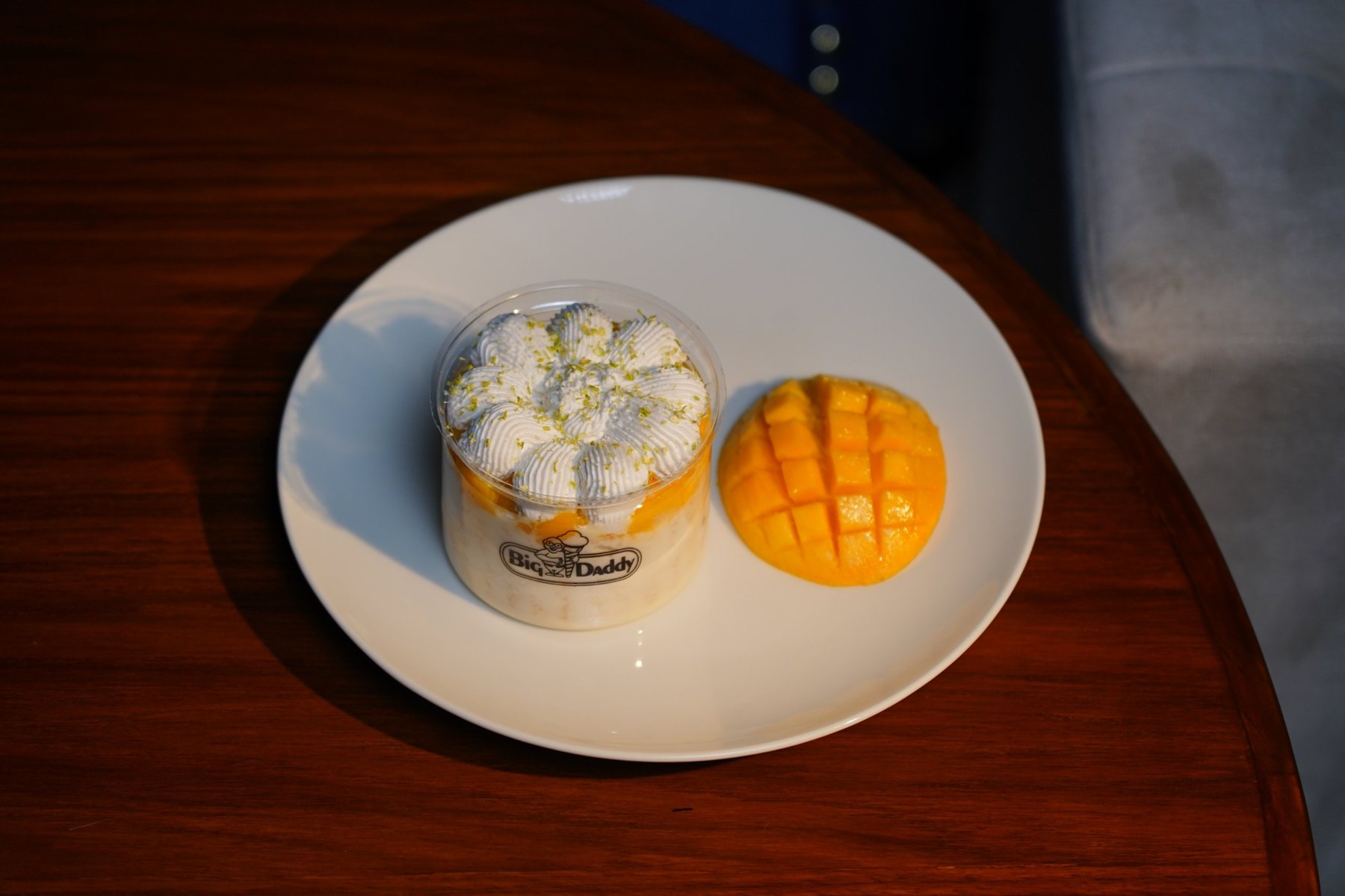 Big Daddy jar dessert with a fresh mango half on a white plate
